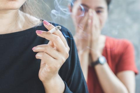 Ejemplo de fumadora pasiva evitando el humo del tabaco