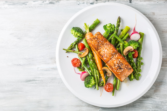 Plato con verdura y salmón, dos alimentos buenos para el corazón.