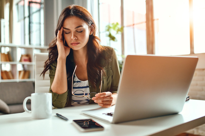 Una mujer con estrés que está bebiendo una infusión para bajar el cortisol.