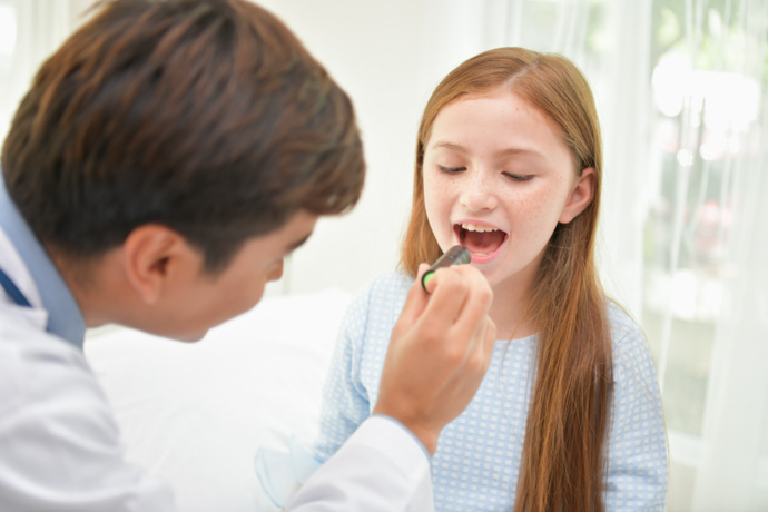 Niña enseñando las llagas de la boca al médico.