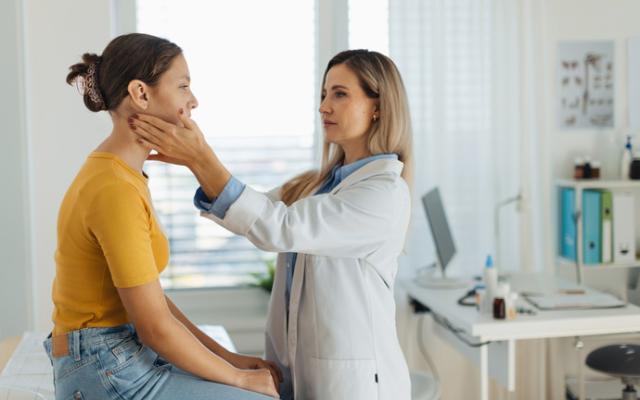 Médico explorando un bulto en el cuello de su paciente