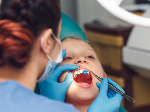 Dentista aplicando flúor en los dientes de un niño.