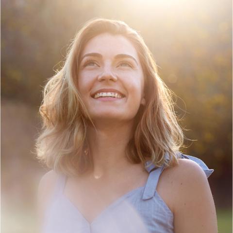 Mujer sonriendo mirando al cielo.