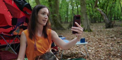 Mujer en una zona de camping buscando señal en su celular.